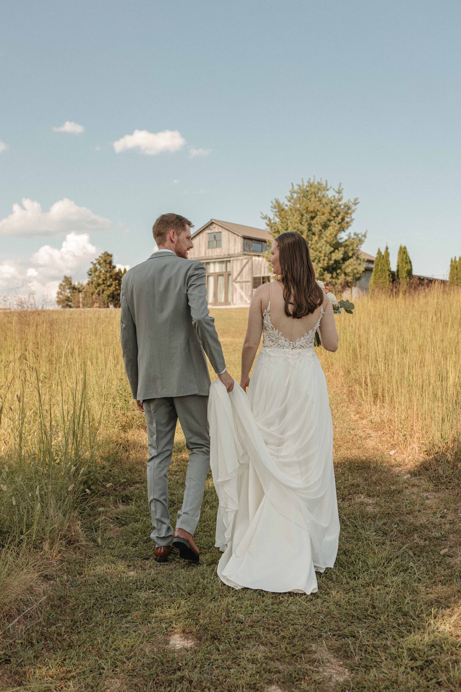 Couple walking hand-in-hand toward the barn
