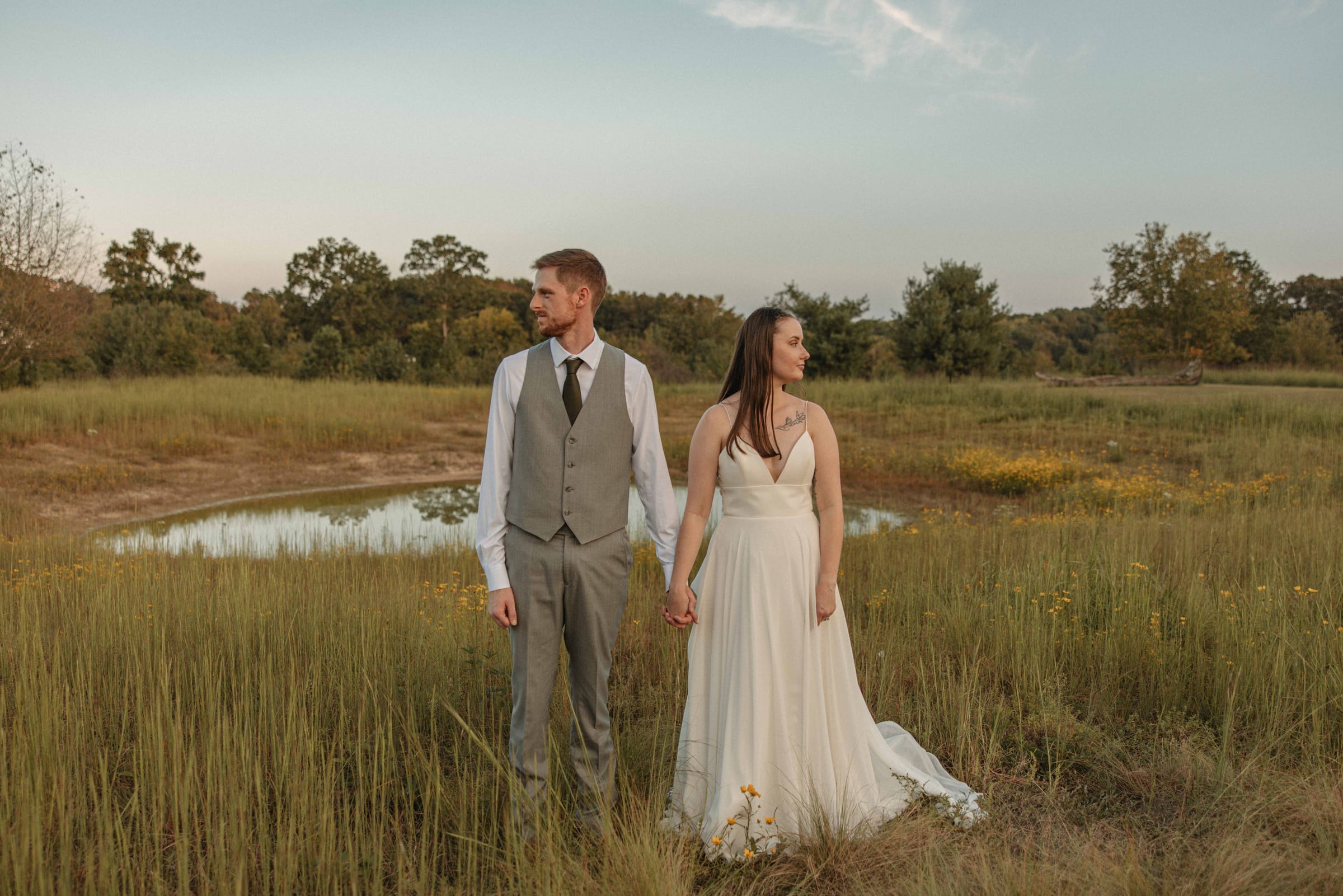 Bride and groom standing at the edge of the meadow pond at golden hour at Cedar Hills Farm