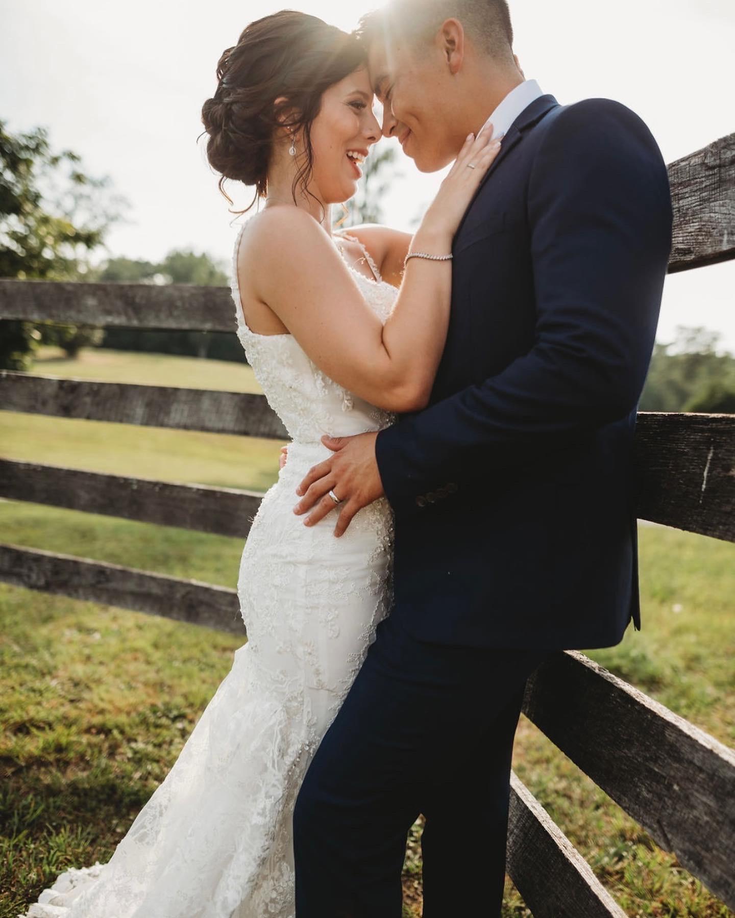 Bride and groom sharing a forehead moment at the wooden farm fence at Cedar Hills Farm
