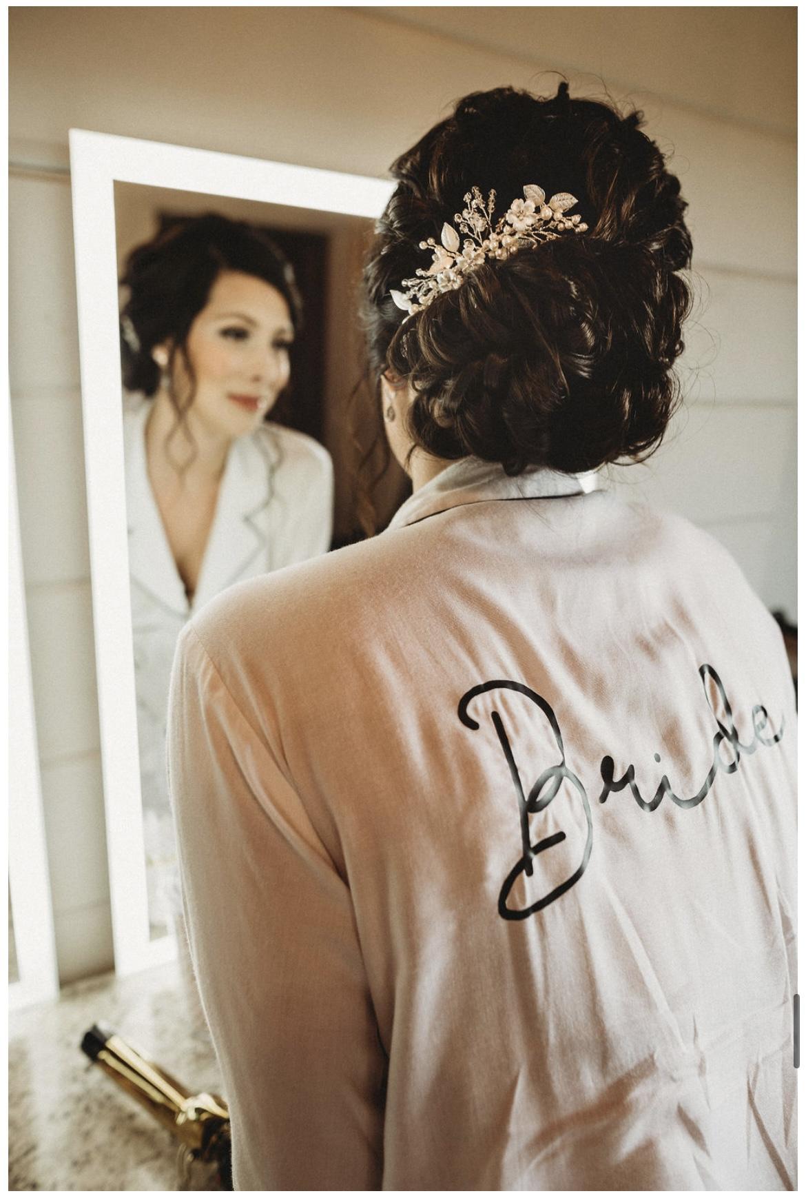Bride in her Bride robe looking at her reflection in the full-length mirror in the bridal suite at Cedar Hills Farm