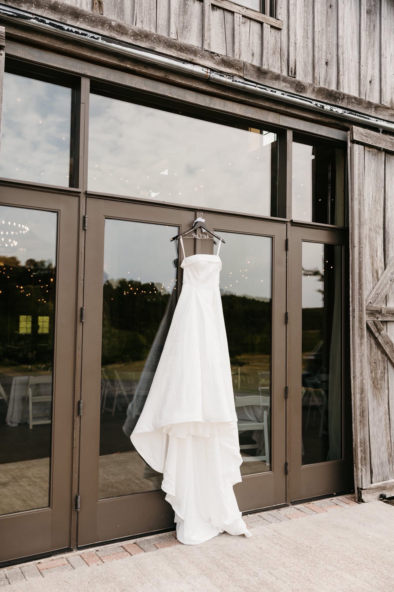 Wedding gown hanging on the exterior doors of the reception barn at Cedar Hills Farm