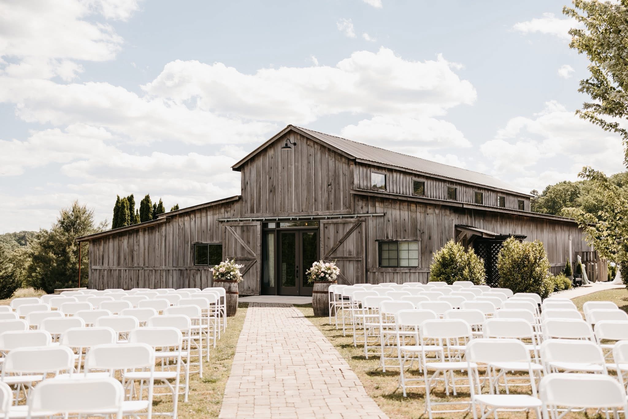 Cedar Hills Farm reception barn exterior with white ceremony chairs set up in rows on the lawn
