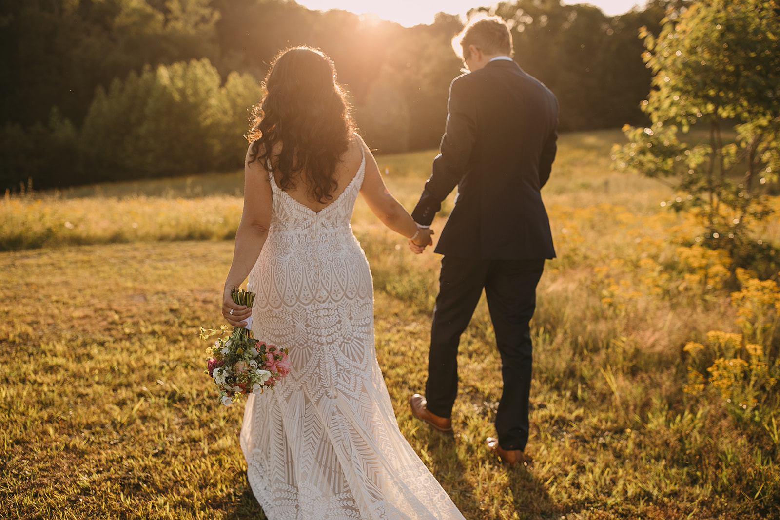 Bride and groom walking hand-in-hand into the sunset at Cedar Hills Farm