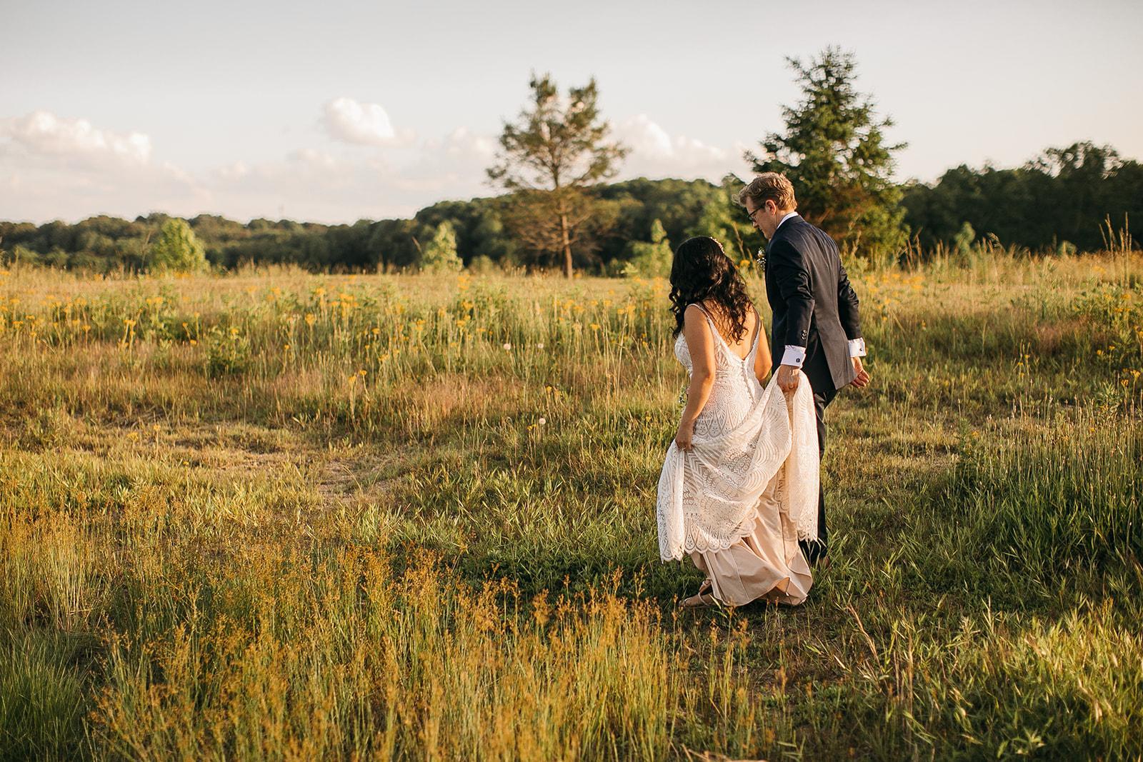 Bride and groom walking through the wildflower meadow at golden hour at Cedar Hills Farm