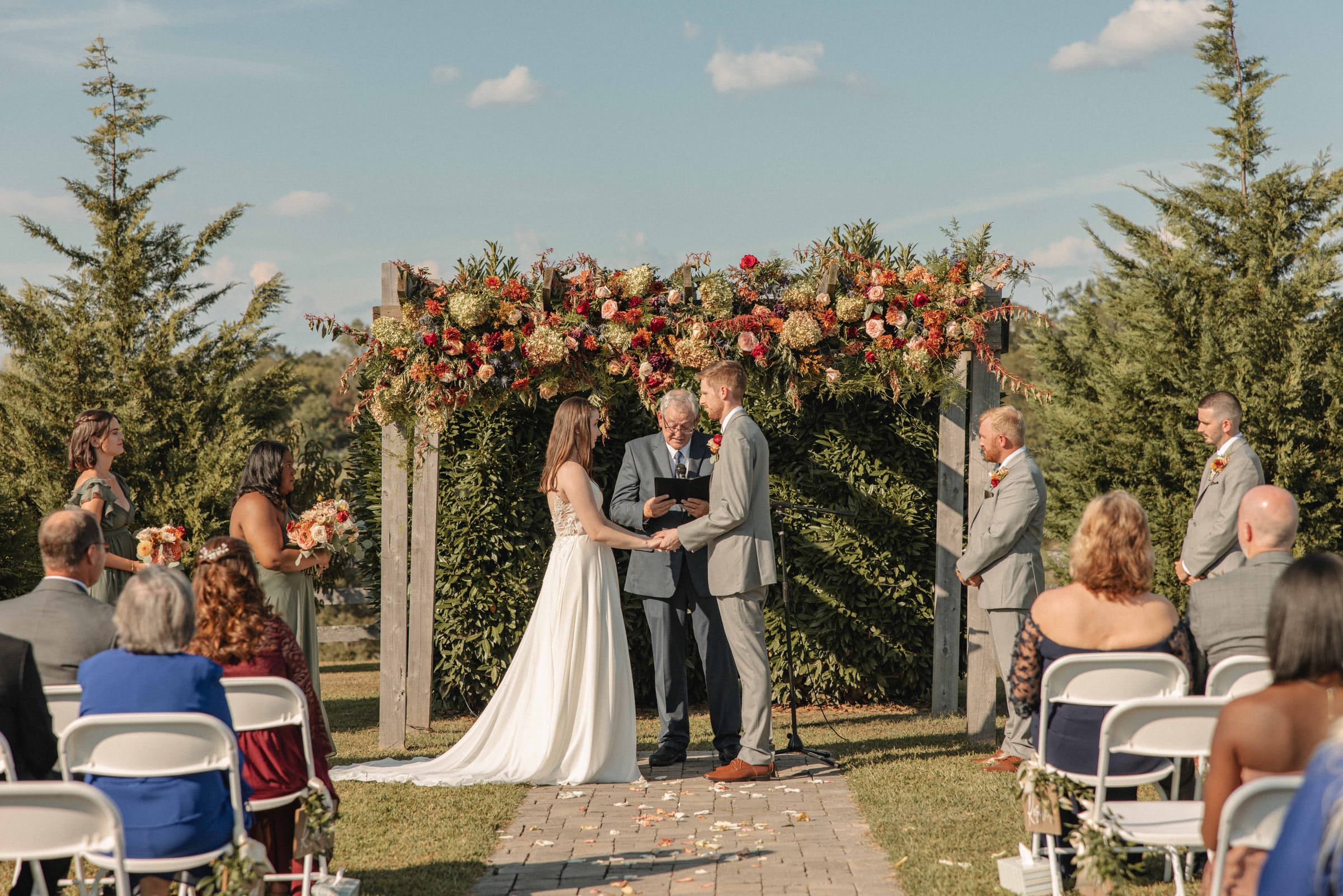 Wedding ceremony at the outdoor altar at Cedar Hills Farm with guests seated on either side